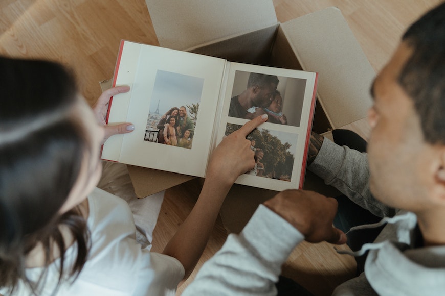 a couple looking at a photo book in a cardboard box.