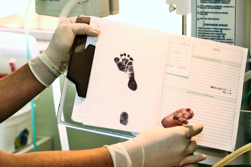 a woman is holding a baby's footprint in a notebook.