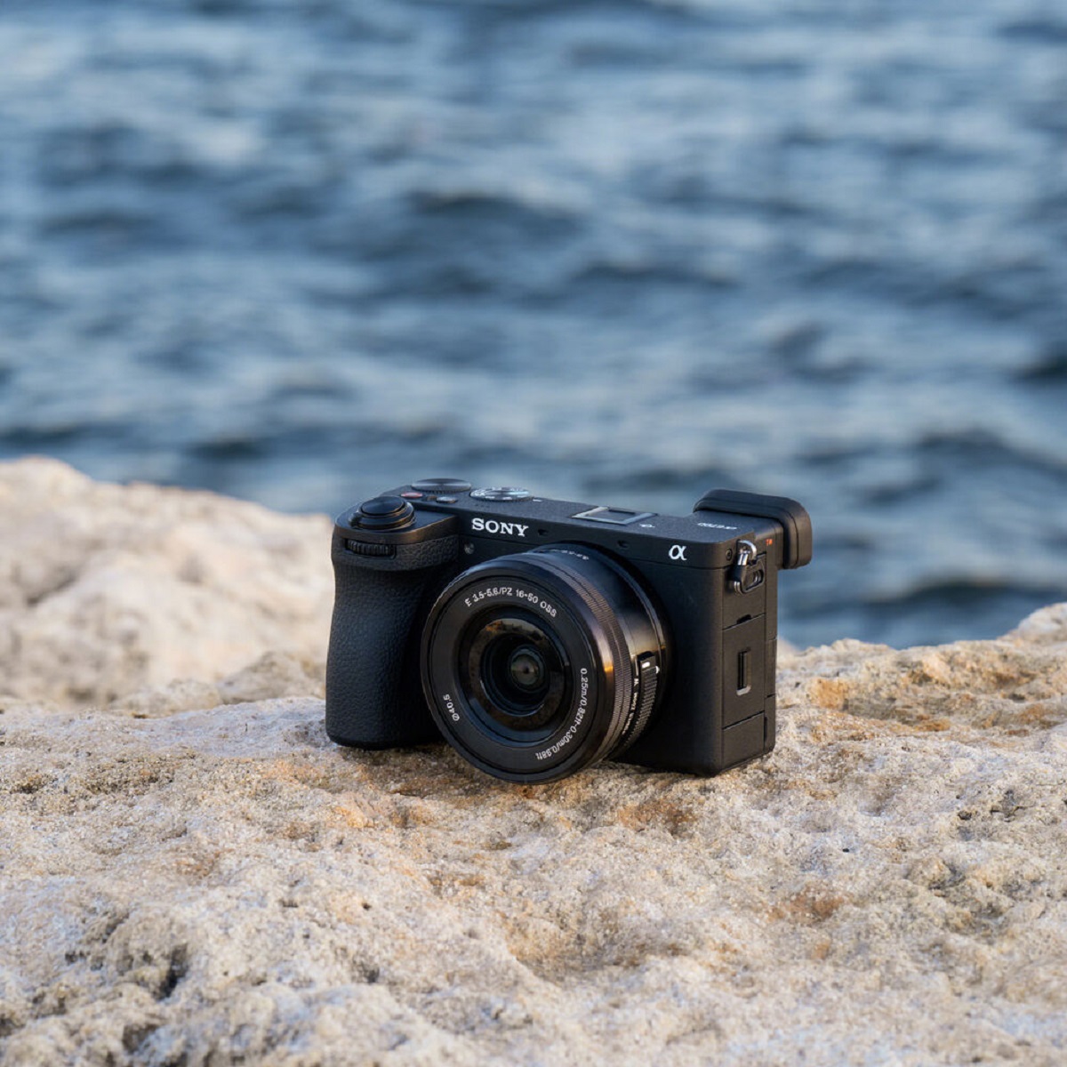 The sony a7ii is sitting on a rock next to the ocean.
