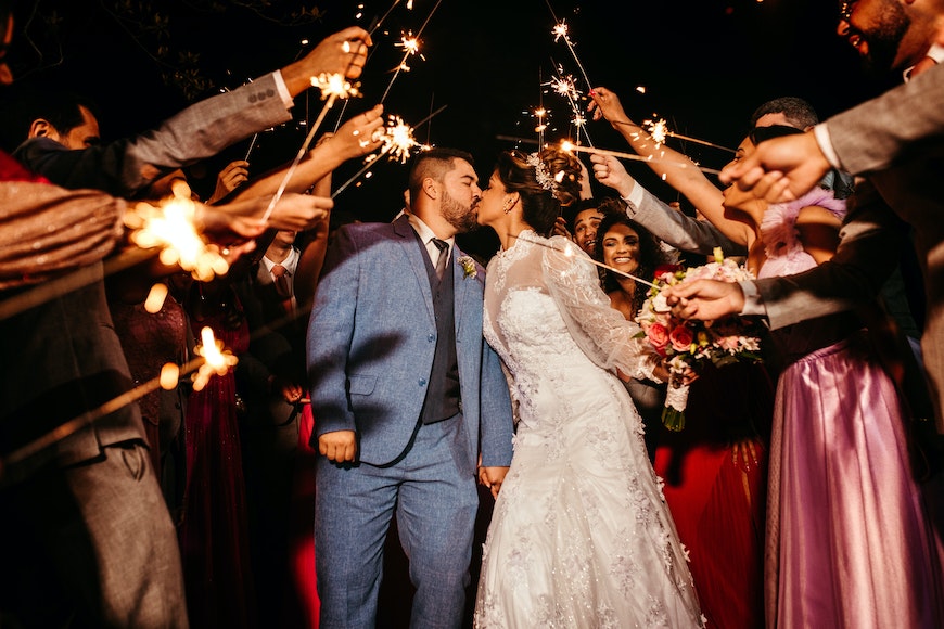 a bride and groom kissing with sparklers.