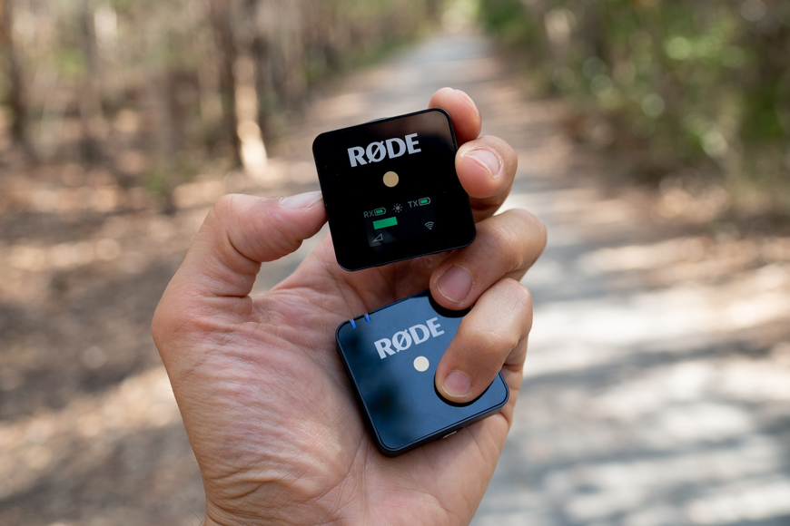 A person holding a wireless transmitter and receiver with the word rode on it.