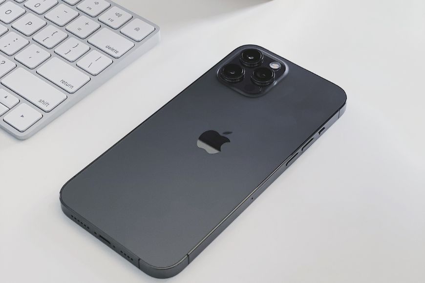 An iphone 11 is sitting on a desk next to a keyboard.
