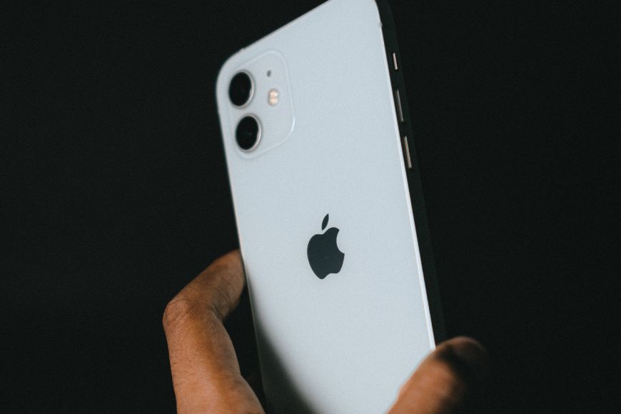 A person holding an iphone 11 on a black background.