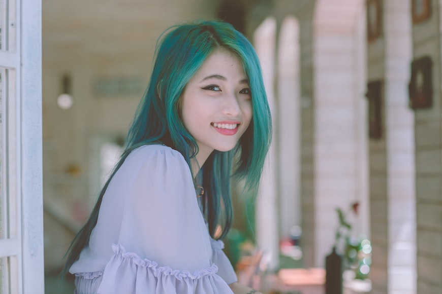 A young asian woman with blue hair posing for a photo.