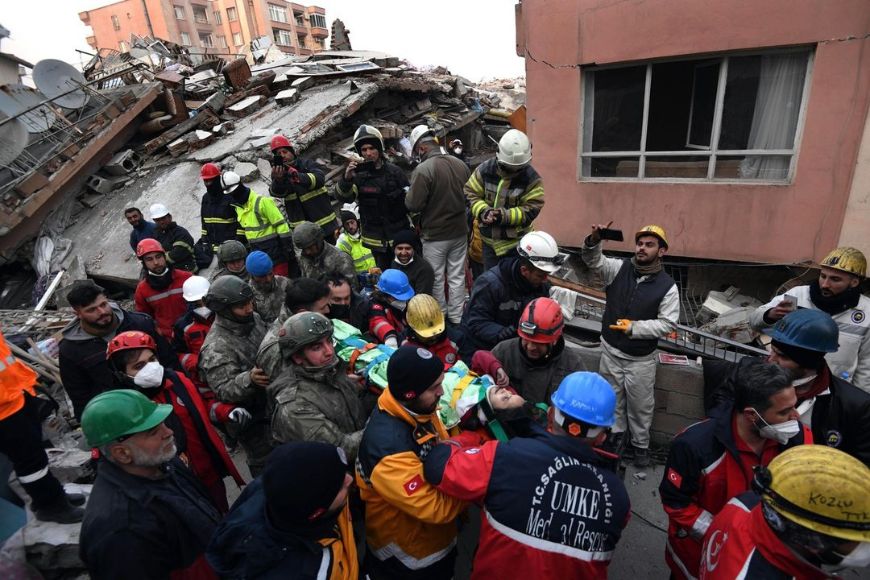 A group of people are gathered around a building that has collapsed.