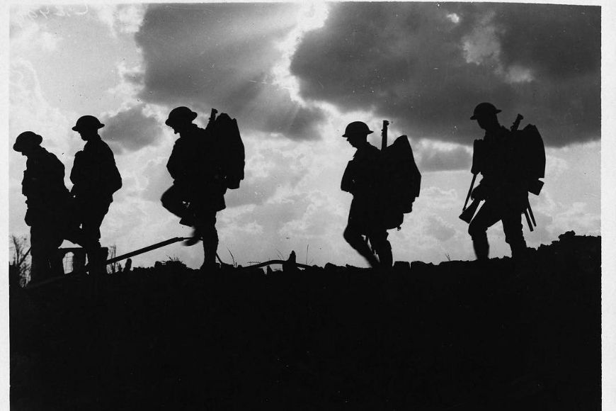 Silhouettes of soldiers walking on a hill.