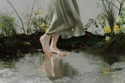 A woman in a green dress standing in a puddle.