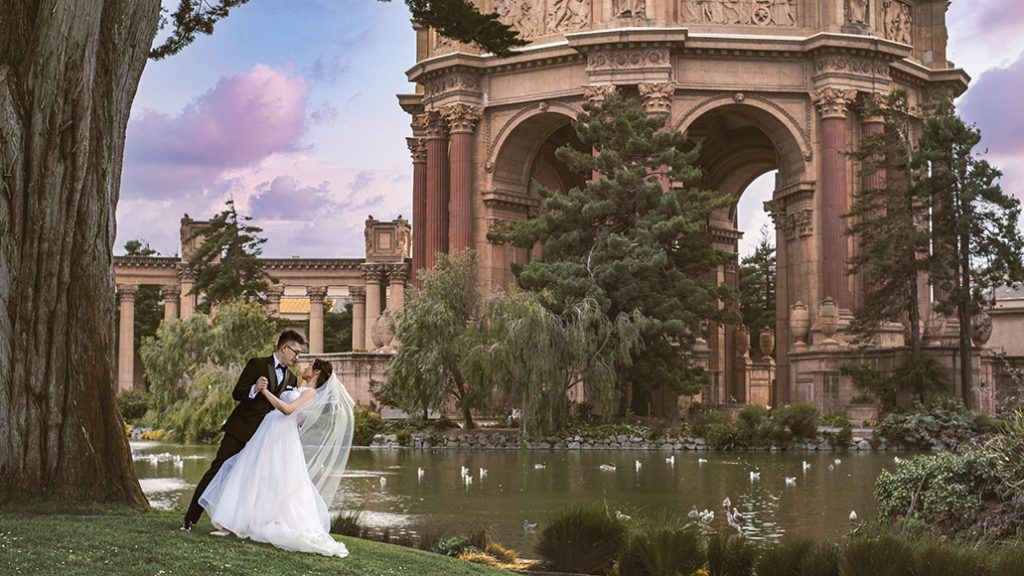 A bride and groom pose in front of the palace of fine arts in san francisco.