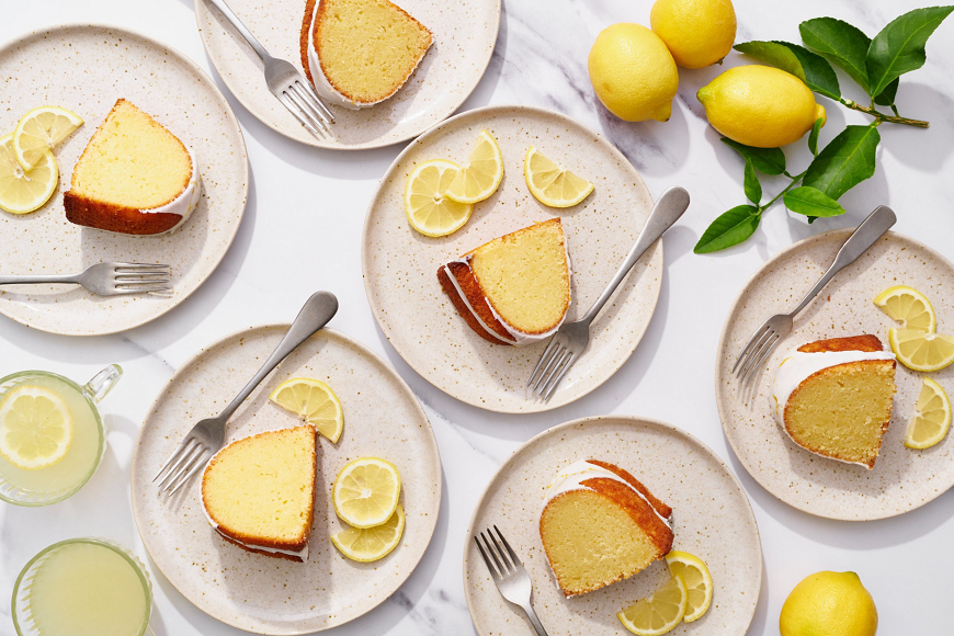 A slice of lemon cake on a plate with lemons on it.