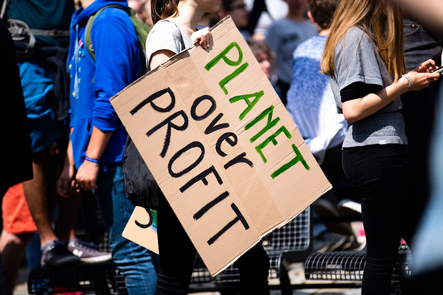 A group of people holding a sign that says planet power profit.