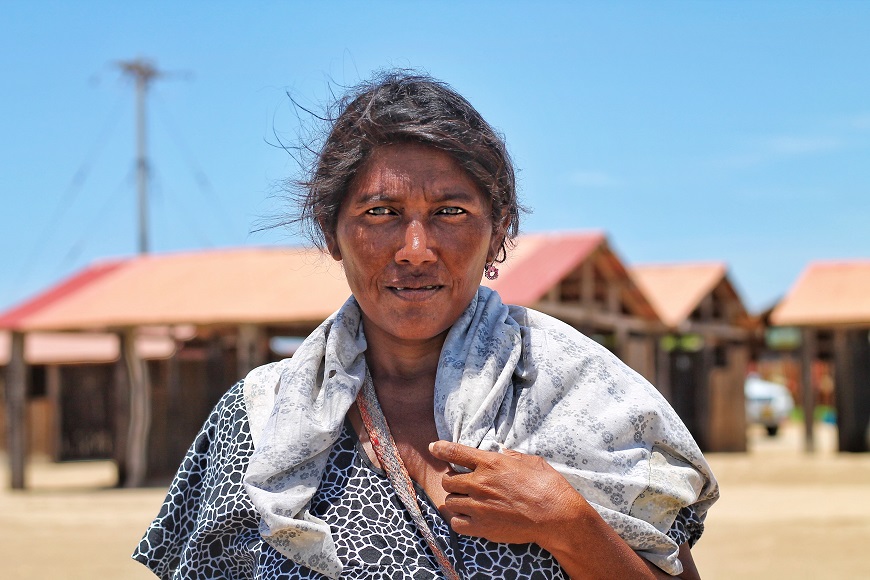 A woman wearing a scarf in front of a shack.
