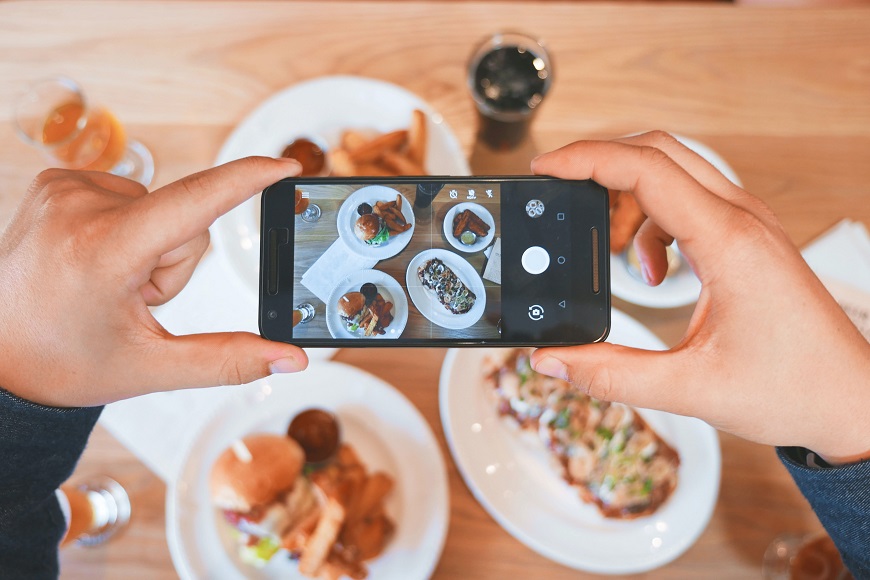 A person taking a photo of food on a table.