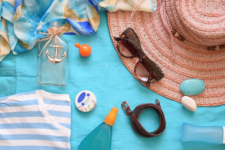 Hat, sunglasses, bottle and other items on a blue background.