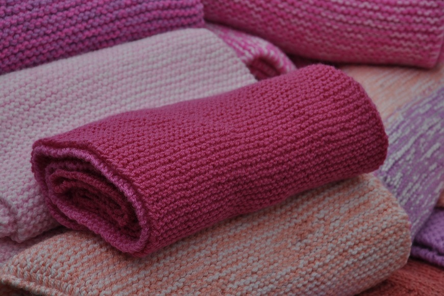 A pile of pink and orange knitted blankets.
