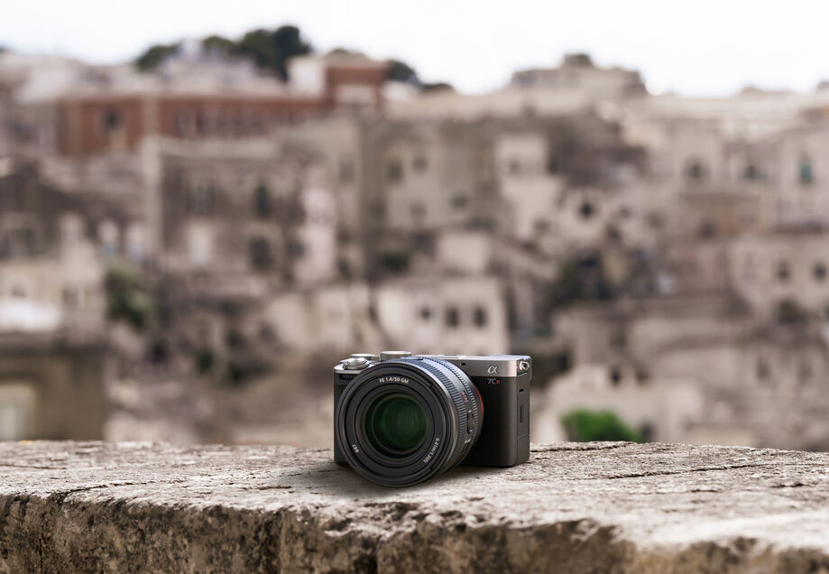 A camera sits on top of a wall with a city in the background.