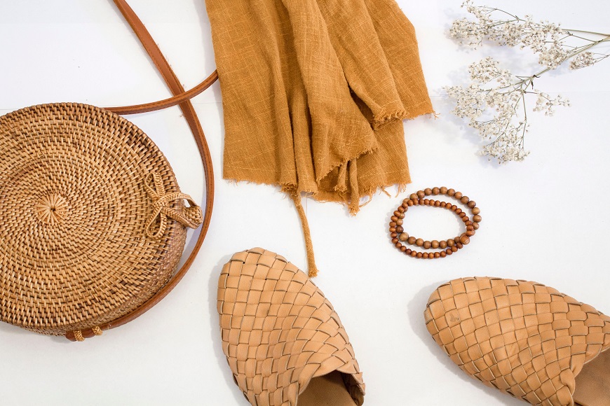 A pair of sandals, a scarf and a bag on a white surface.