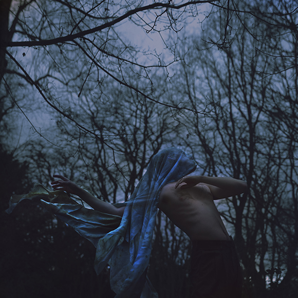 A person in the woods with a blue scarf.