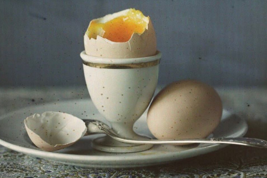 A broken egg on a plate with a spoon.