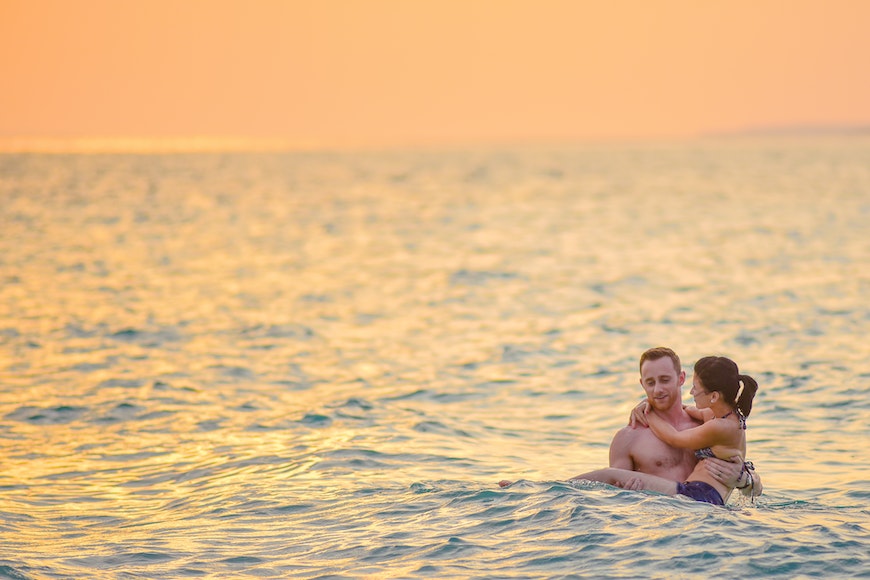 A couple in the ocean at sunset.