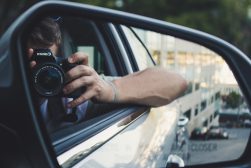 A man is taking a picture in the rear view mirror of a car.