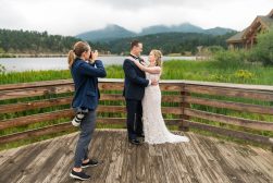 A bride and groom pose for a photo on a wooden bridge.