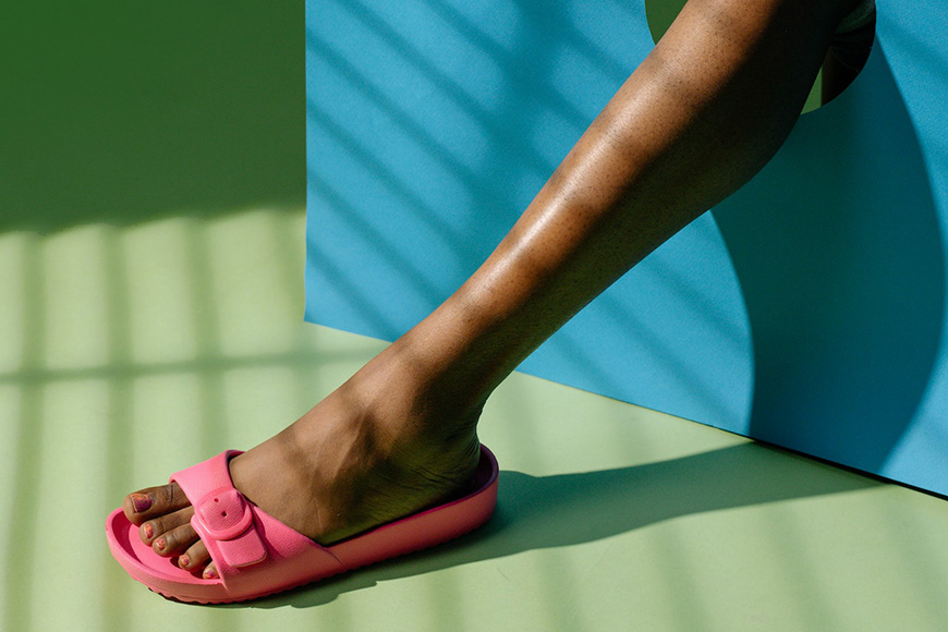 A woman's legs in a pair of pink sandals.