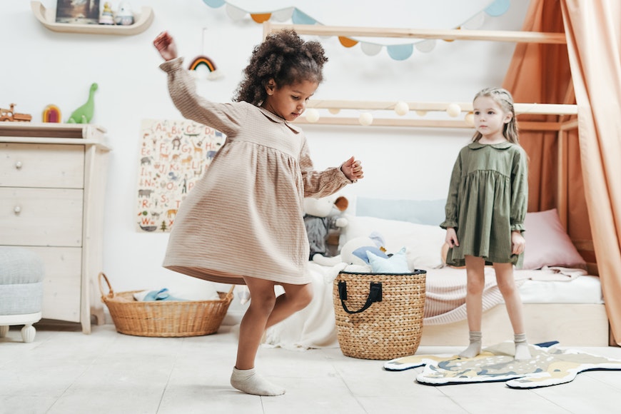 Two little girls dancing in a room.