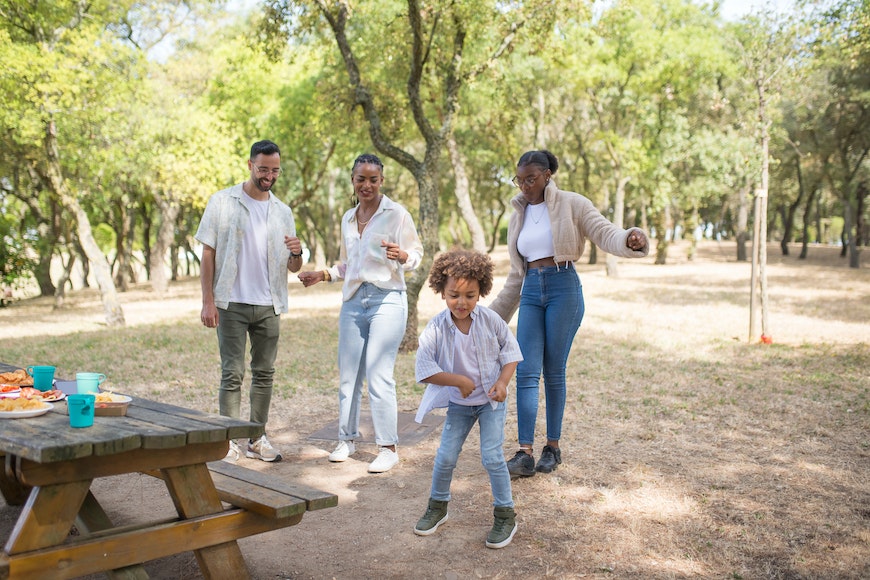 A family is having fun at a picnic table in a park.