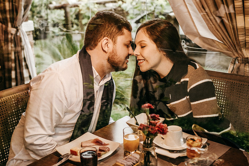 A couple kissing at a table in a restaurant.