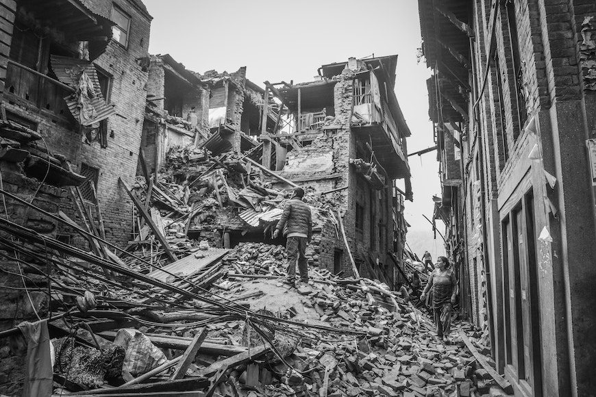 A man is standing in the rubble of a building.
