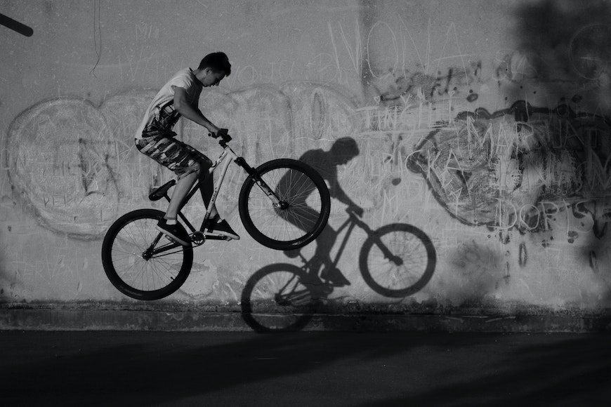 A man riding a bike in front of graffiti.