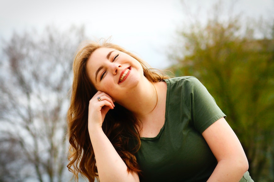 A young woman is smiling while sitting on a bench.