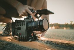 A person holding a camera on a road.