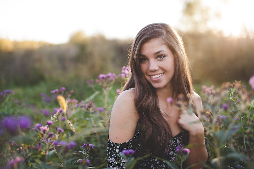 A young woman sitting in a field of purple flowers.