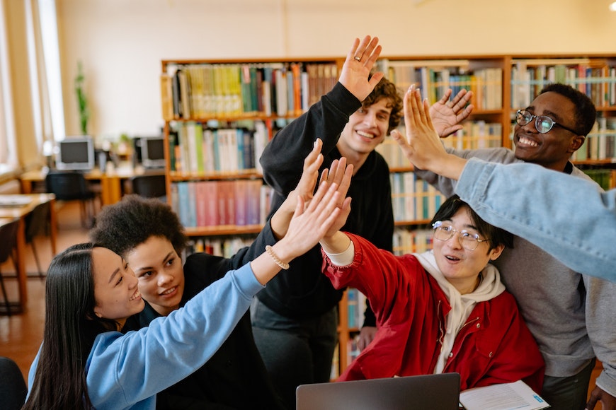A group of people giving each other high fives in a library.