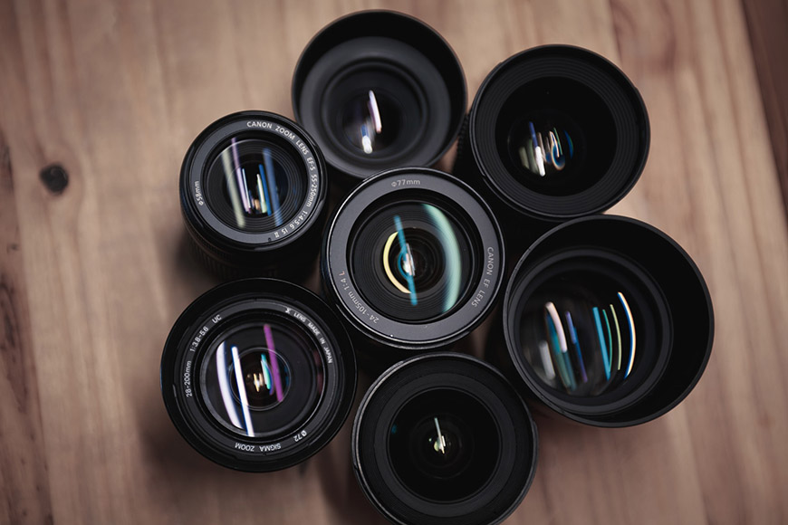 A group of camera lenses on a wooden surface.