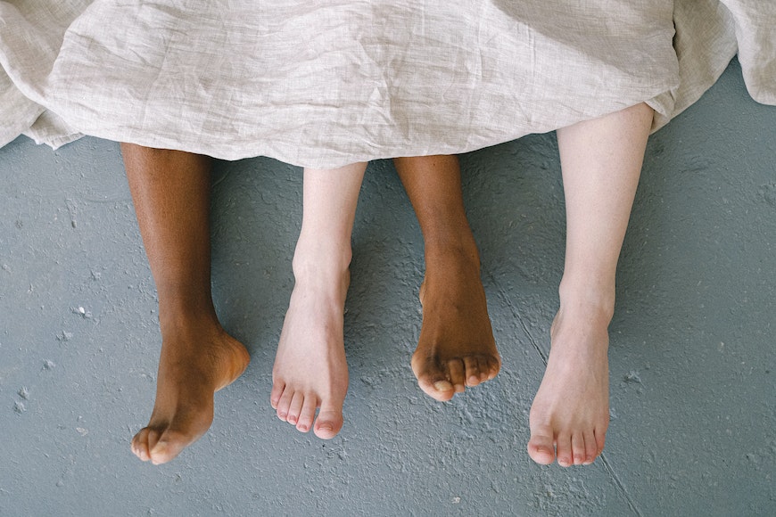 Women's feet under a blanket.