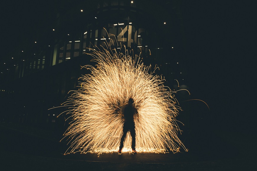 A person standing in front of a building with a sparkler.