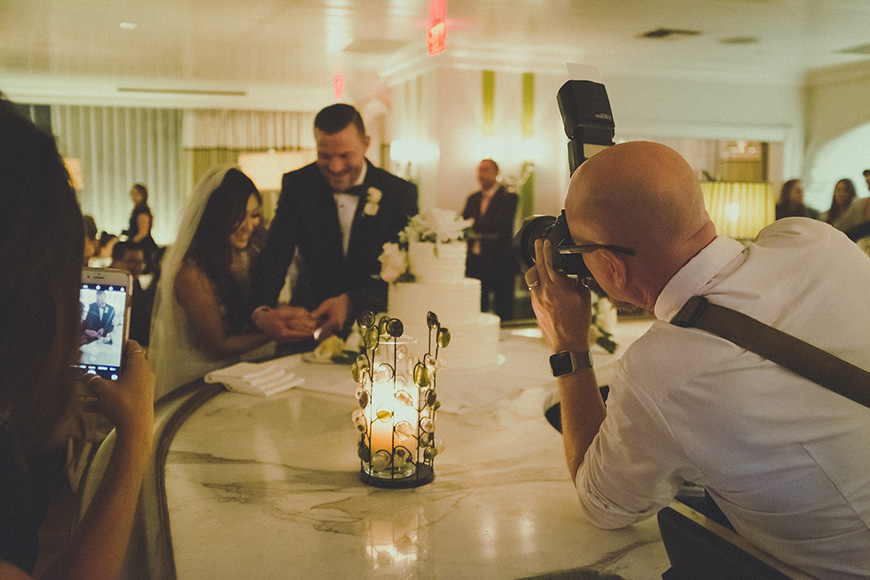 A bride and groom taking pictures at a wedding reception.