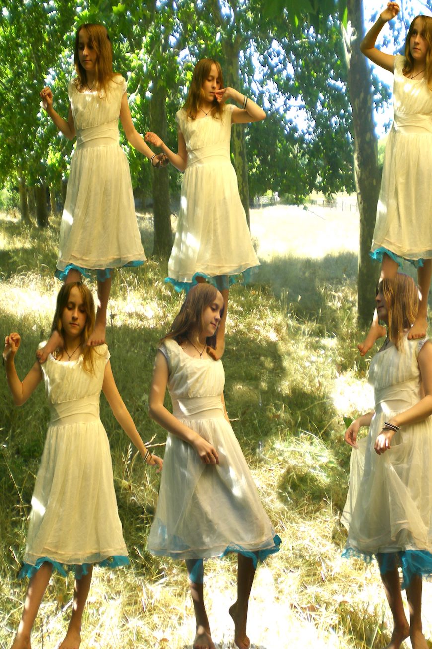 A woman in a white dress posing in the woods.