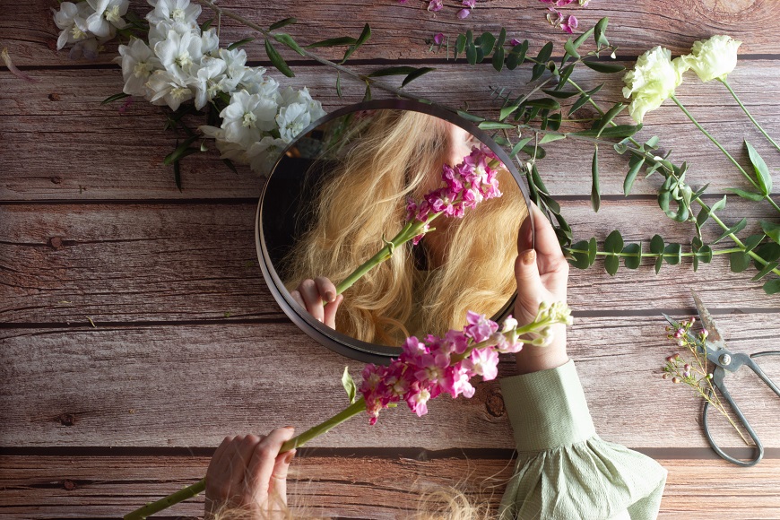 A woman is holding a bouquet of flowers in front of a mirror.