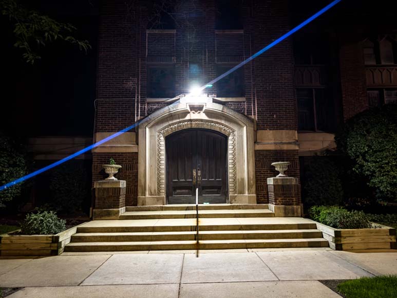 A blue light shines on the steps of a building at night.
