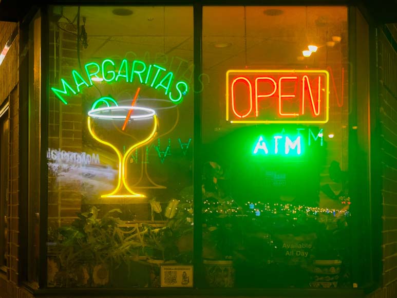 A neon sign with a margarita sign in the window.