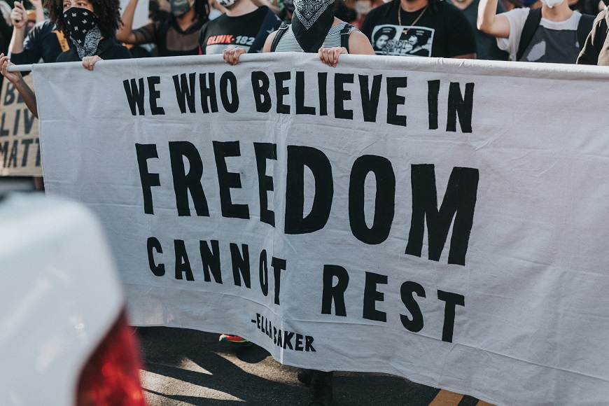 A group of people holding a banner that says we who believe in freedom can't rest.