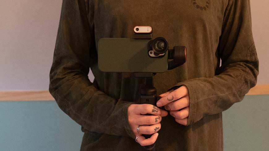 A man holding a phone with a gimbal attached to it.