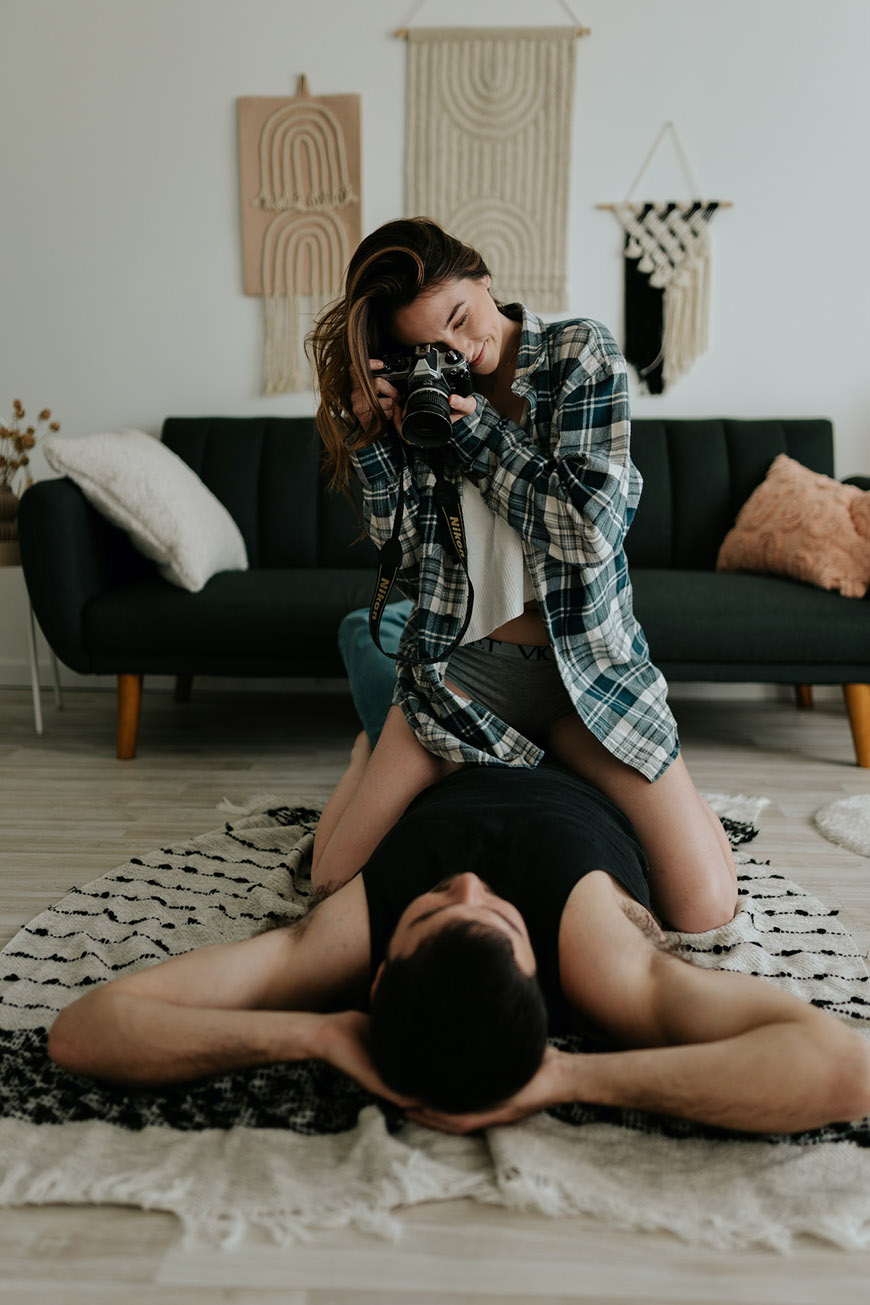 A man and woman taking a picture of each other in a living room.