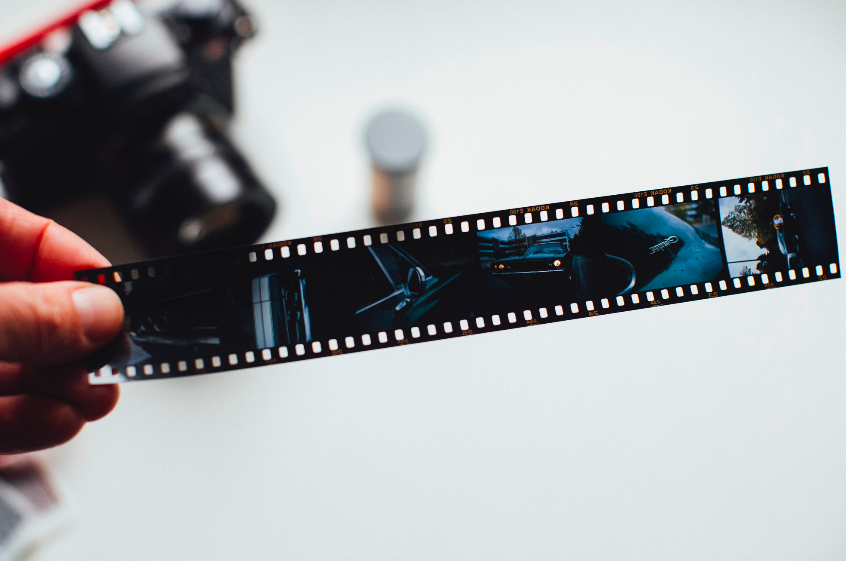 A person holding a film strip with a camera.