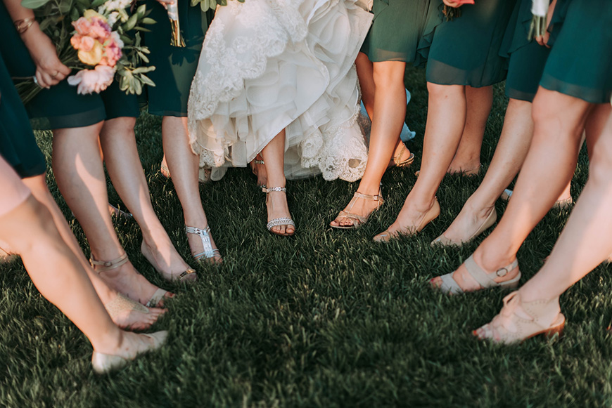 A group of bridesmaids standing in a circle showing their feet.