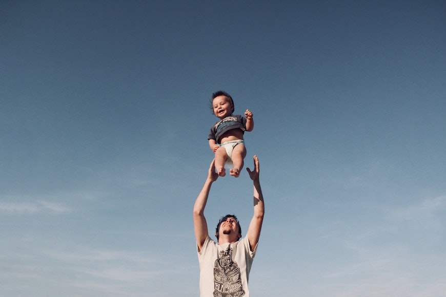 A man holding a baby up in the air.