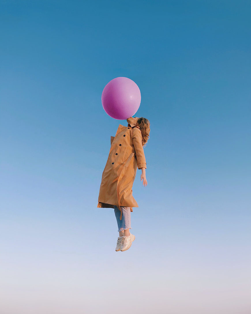 A woman is holding a pink balloon in the air.